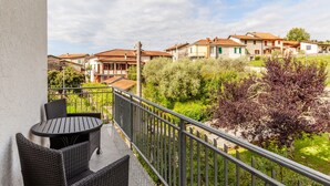 A balcony with wicker furniture, a view of houses, and greenery. - Villa La Lanterna Bianca Apartment with Mountain View, Wi-Fi, and Air Conditioning (Bagnone)