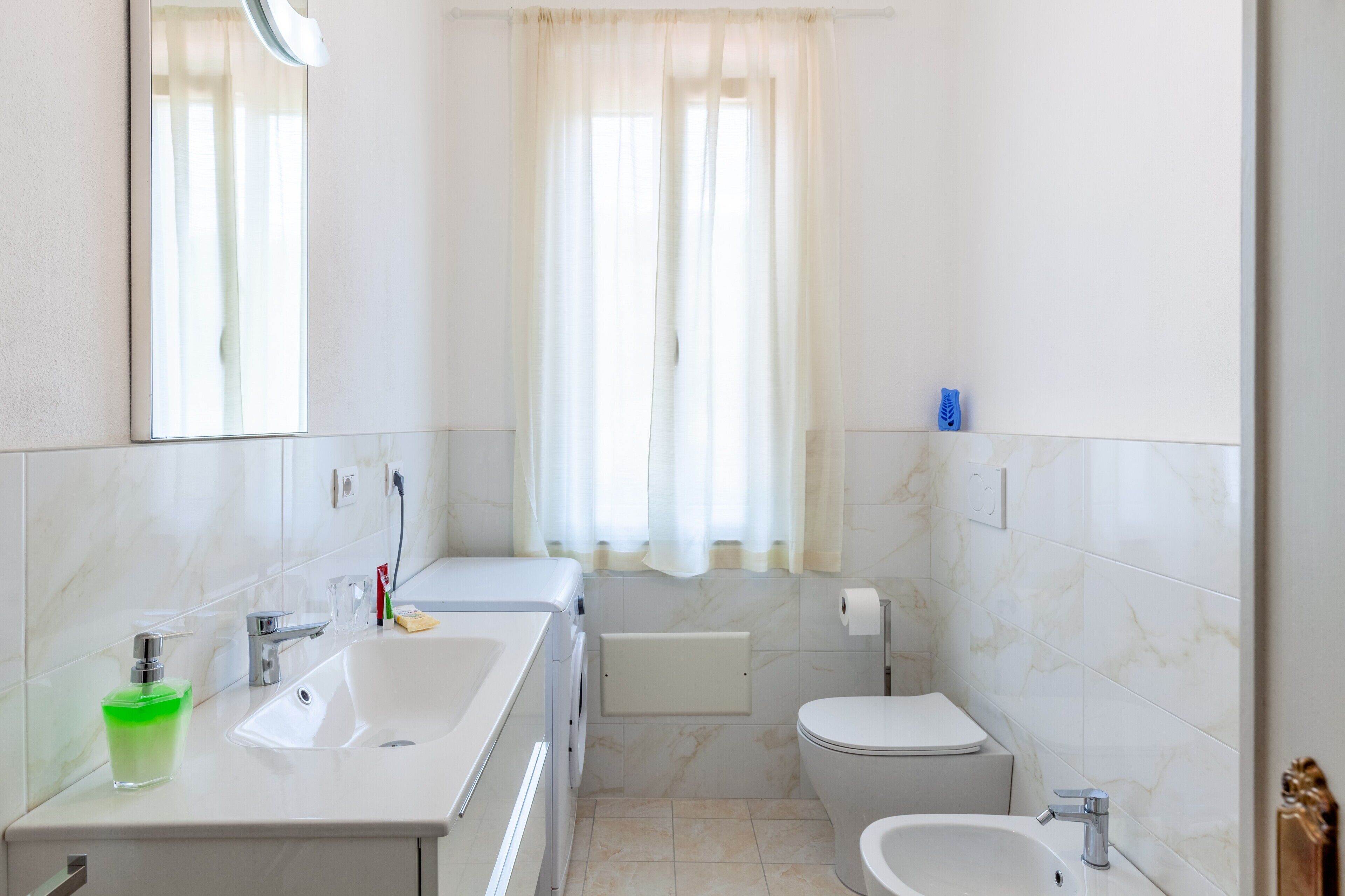 A modern bathroom with a sink, toilet, bidet, and a mirror.