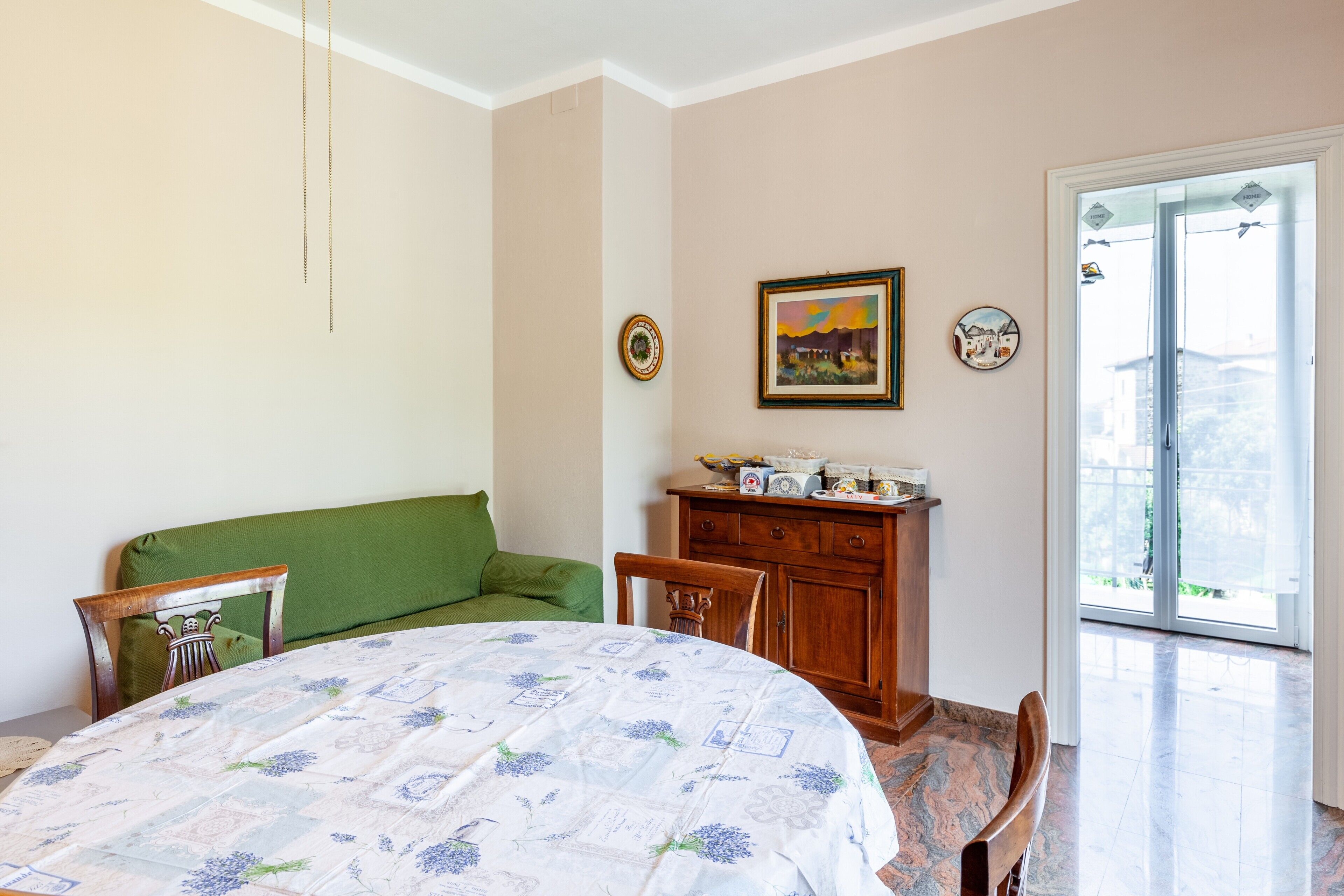 Una camera da letto con un letto, un divano verde, un armadietto in legno e una porta che dà su un balcone.
