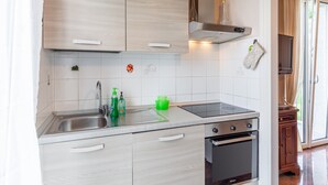 A modern kitchen with a stainless steel sink, a built-in oven, and light wood cabinetry. - Villa La Lanterna Bianca Apartment with Mountain View, Wi-Fi, and Air Conditioning (Bagnone)