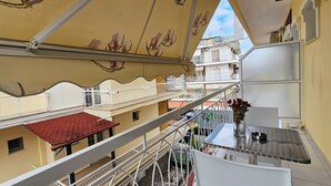 A multi-story building with balconies, a red-tiled roof, and a flower vase on a table. - Chariclia Hotel (Katerini)