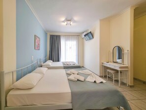 A hotel room with two beds, a desk with a mirror, a flat-screen TV, and a window with curtains.