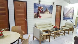 Um saguão de hotel com um conjunto de sofás, cadeiras, uma mesa de centro e uma pintura de um camelo.