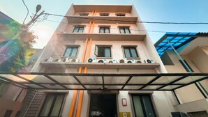 Um edifício com vários andares, teto plano, grandes janelas e aparelhos de ar condicionado na fachada.