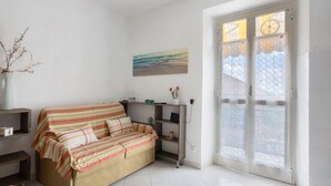 A room with a sofa, a painting, a vase with flowers, and a door with a window. - Apartment 'Da Ercolino' with Sea View, Balcony and Wi-Fi (Pitelli)