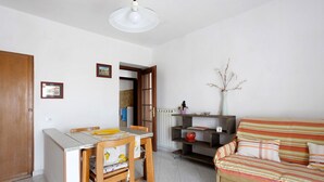A living room with a sofa, a dining table with chairs, a kitchen area, and a door leading to another room. - Apartment 'Da Ercolino' with Sea View, Balcony and Wi-Fi (Pitelli)