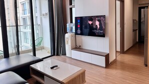 A modern living room with a flat-screen TV, a ceiling fan, and a water dispenser. - Mira Housing- Vinhome Skylake Luxury Apartment  (Hanoi)