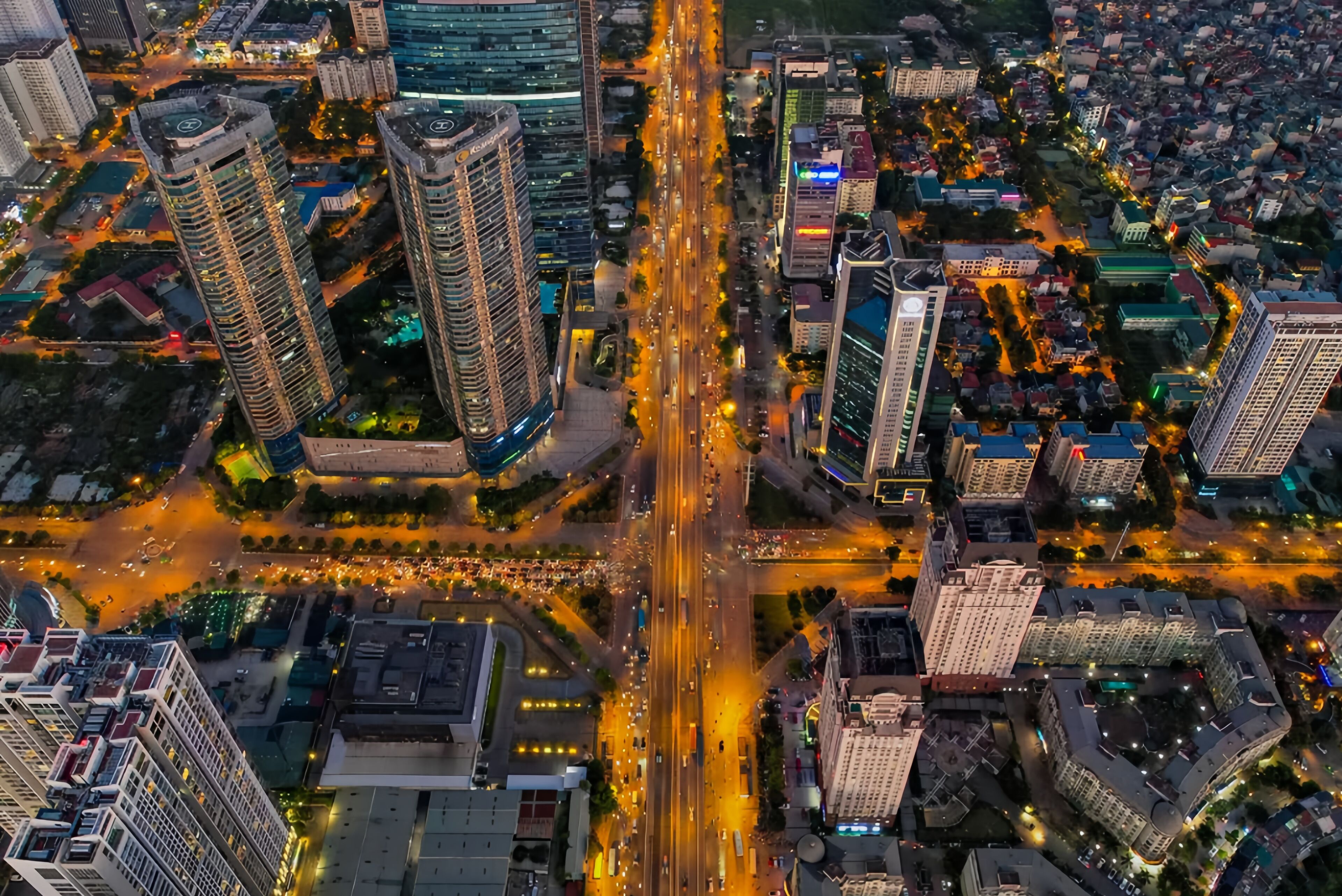 Vista aérea de un paisaje urbano con rascacielos, una intersección con mucho tráfico y calles bien iluminadas.