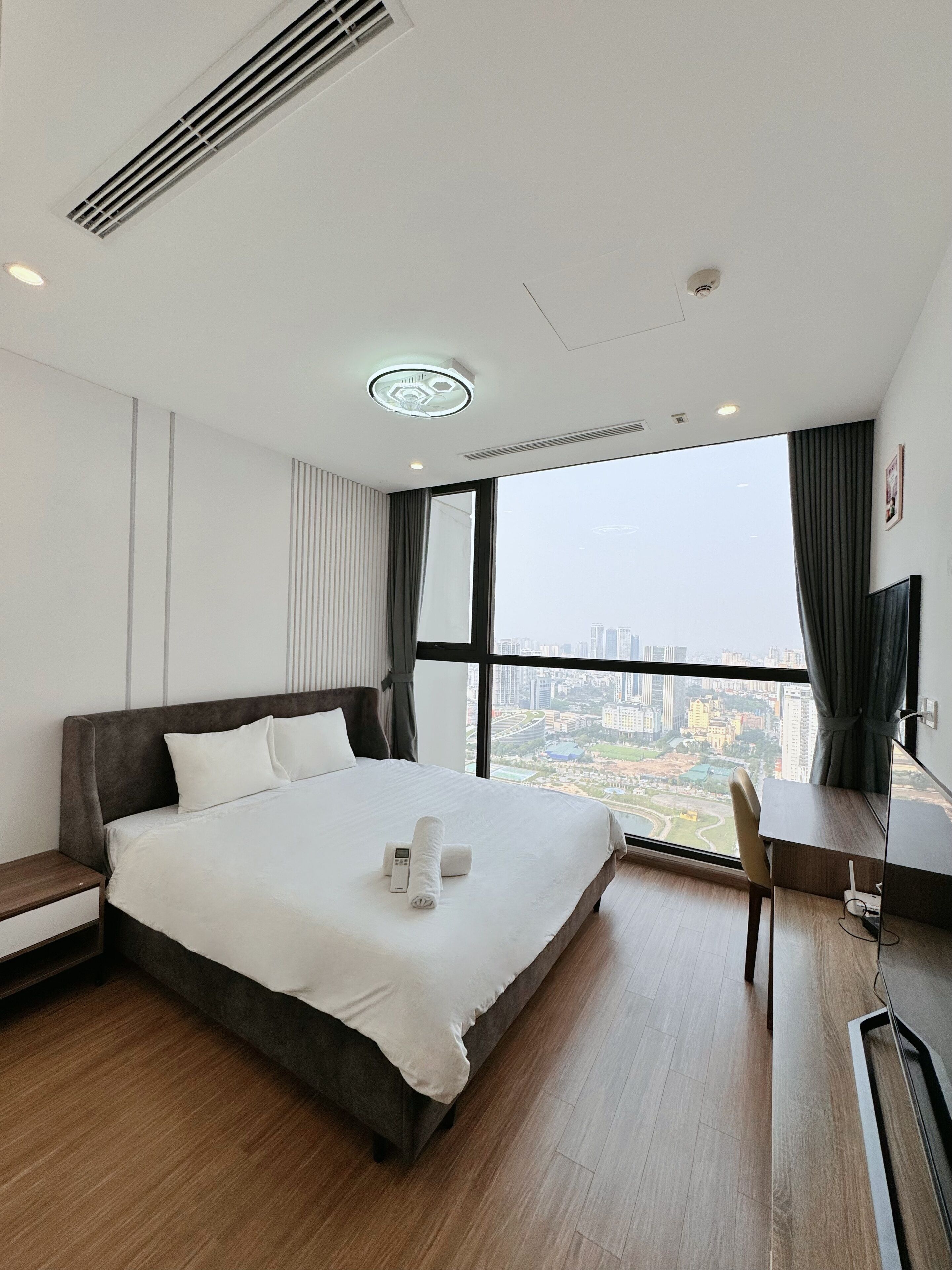 Une chambre d’hôtel moderne, dotée d’un grand lit, d’un bureau et offrant une vue sur la ville.