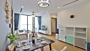 A modern living room with a dining area, a large window, and a decorative wall clock. - Mira Housing- Vinhome Skylake Luxury Apartment  (Hanoi)