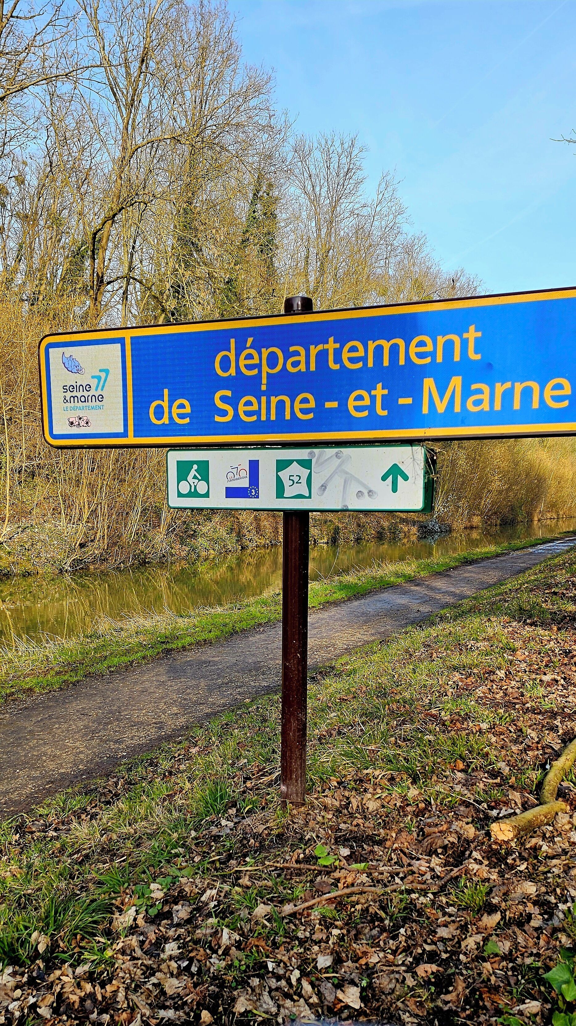 A directional sign for 'departement de Seine-et-Marne' with symbols for cycling routes and a number '52'.