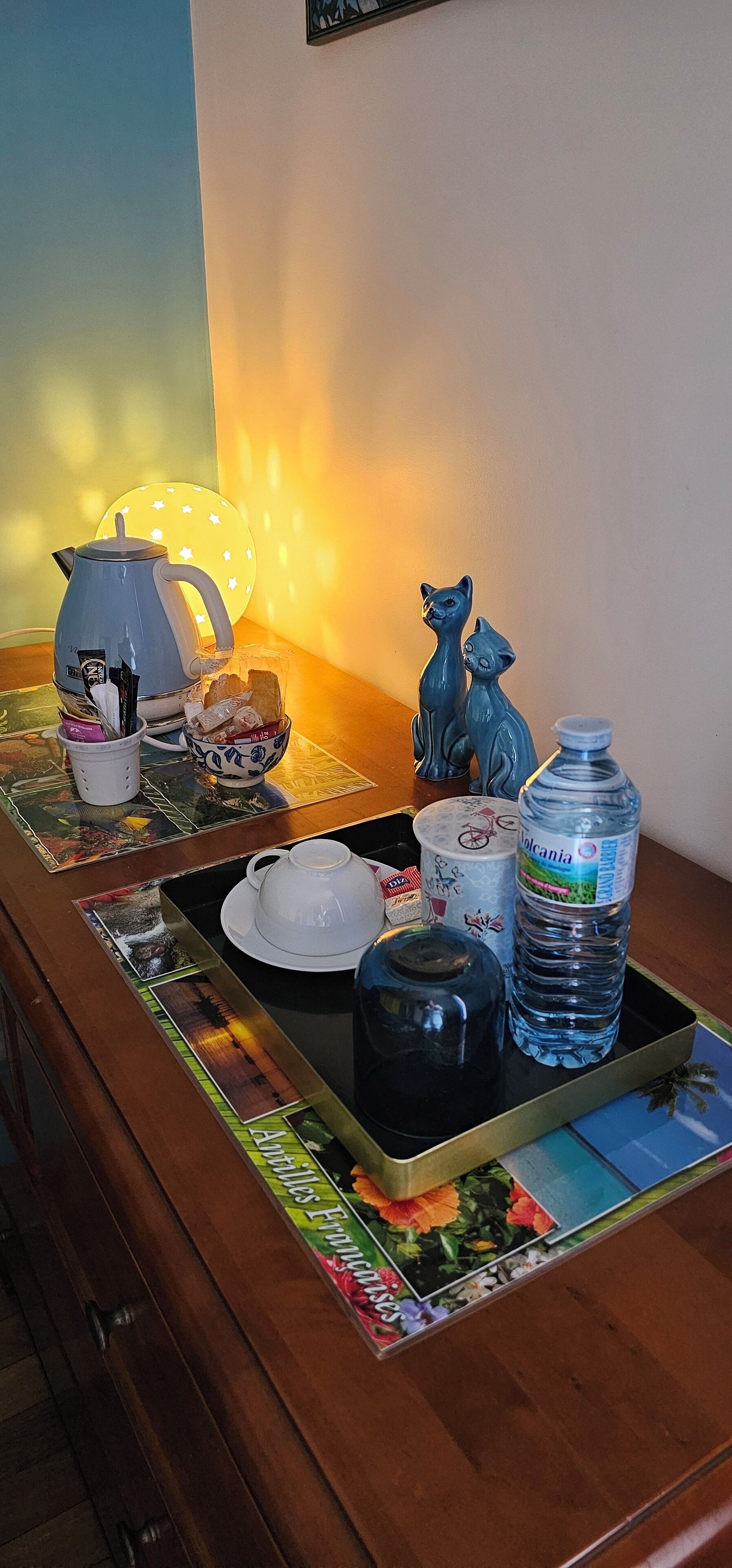 A table with a teapot, cups, a water bottle, and decorative items.