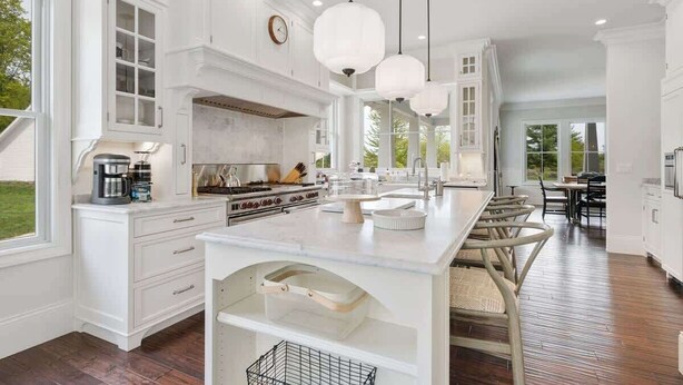 A spacious kitchen with white cabinetry, a large island, and pendant lighting. - Lost Lane | Luxury Retreat w/ Hot Tub & Trails (Ellison Bay)