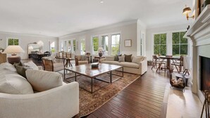 A spacious living room with a large coffee table, sofas, and a fireplace. - Lost Lane | Luxury Retreat w/ Hot Tub & Trails (Ellison Bay)