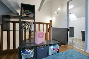 A room with a bookshelf, a desk, and storage bins.