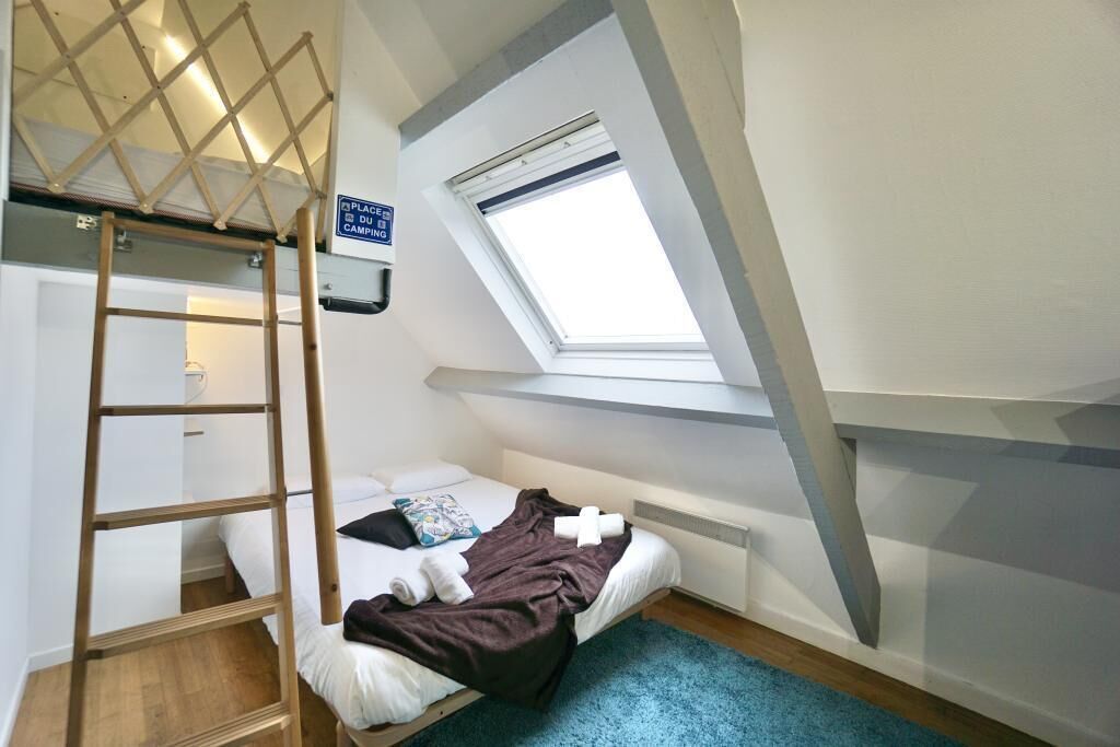A small, single-bed room with a skylight, a wooden ladder, and a sign indicating a place for camping.