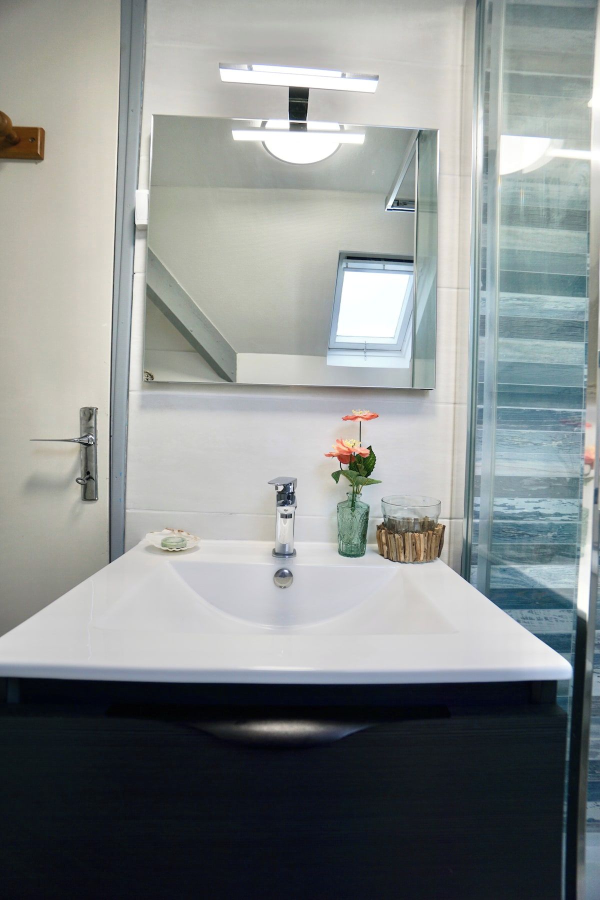 A bathroom with a white sink, a mirror, a window, and a door.