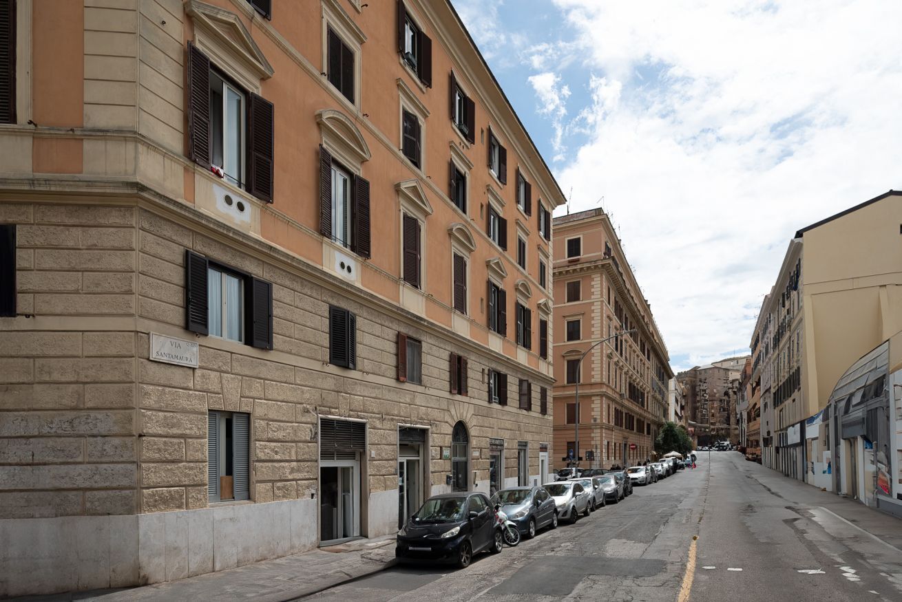 A street with parked cars and buildings with multiple windows and doors.