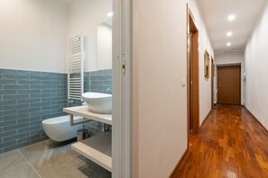 A modern bathroom with a white sink, a toilet, and a towel rack.