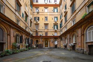 A courtyard with a central open space surrounded by buildings with arched doorways and windows.
