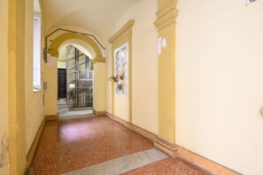 A corridor with a tiled floor, yellow walls, and a door with a window. - Gracchi Apartment Prati (Roma)