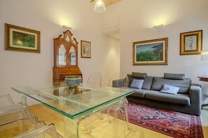 A living room with a glass table, a sofa, and framed artwork on the walls. - Gracchi Apartment Prati (Roma)
