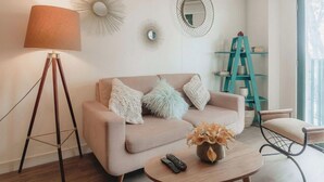 A living room with a sofa, a coffee table, a lamp, a mirror, and a ladder. - Elegance in Barranco - Cozy 2BR (Barranco)