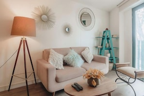 Een woonkamer met een bank, een salontafel, een lamp, een spiegel en een ladder.
