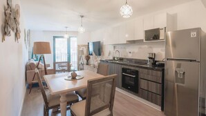 A modern kitchen with a dining table, chairs, a refrigerator, and a microwave. - Elegance in Barranco - Cozy 2BR (Barranco)
