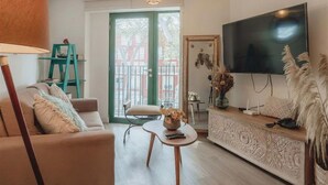 A living room with a sofa, a coffee table, a TV, and a door leading outside. - Elegance in Barranco - Cozy 2BR (Barranco)
