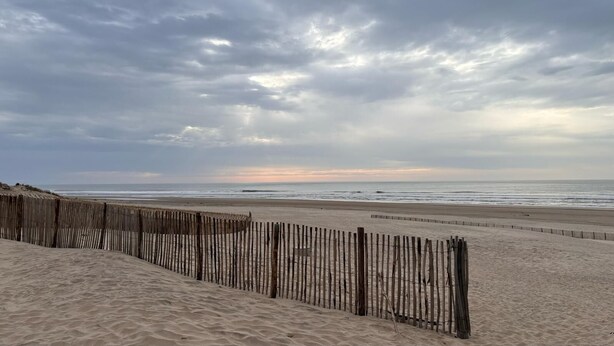 A sandy beach with a wooden fence and the ocean in the background. - Petit Cocon a 150m de L'océan (Soulac-sur-Mer)