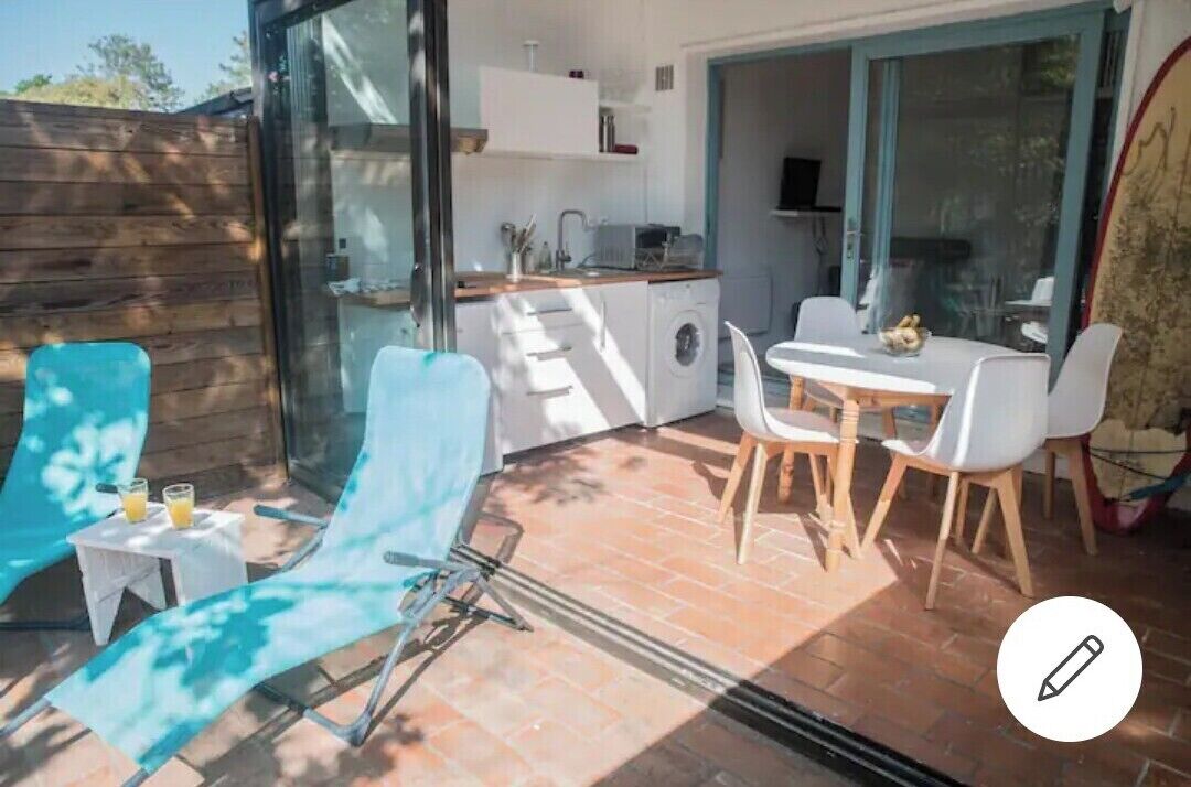 A modern kitchen with a dining area, a washing machine, and a glass door leading to a patio.