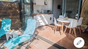 A modern kitchen with a dining area, a washing machine, and a glass door leading to a patio. - Petit Cocon a 150m de L'océan (Soulac-sur-Mer)