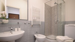 Une salle de bain moderne équipée d’un lavabo, d’un bidet, de toilettes et d’une douche à parois de verre.