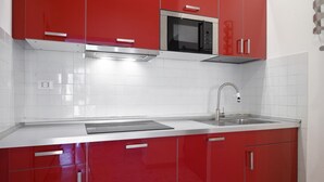 Una cocina moderna con armarios rojos, un microondas de acero inoxidable y un fregadero.