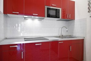 A modern kitchen with red cabinets, a stainless steel microwave, and a sink. - Opera 65 Roof Terrace (Roma)