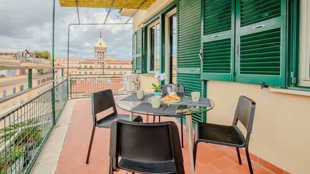 Un balcon avec une table, des chaises et une vue sur un bâtiment surmonté d’un dôme.