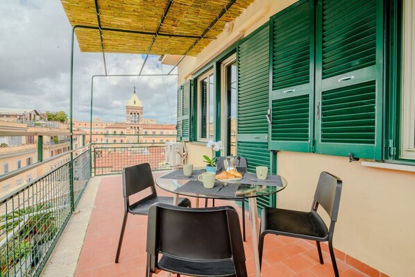 A balcony with a table, chairs, and a view of a building with a dome.