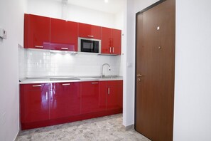 Una cocina con gabinetes rojos, un microondas y un fregadero.