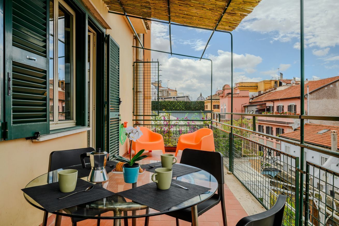 Un balcone con tavolo, sedie e una pianta in vaso.