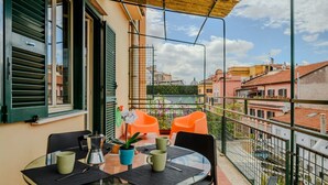 Un balcon avec une table, des chaises et un pot de fleurs.