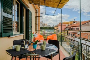 A balcony with a table, chairs, and a potted plant.