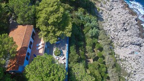 An aerial view of a coastal property with a terraced garden, a building with a tiled roof, and a rocky shoreline. - Villa Majus - with swimming pool and direct access to the sea in marine protected area  (BAGHERIA)