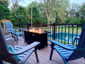 Une terrasse avec coin salon extérieur et foyer, donnant sur une piscine.
