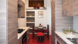 Een moderne keuken met houten kastjes, een eettafel gedekt voor vier personen, en een rode beklede bank.