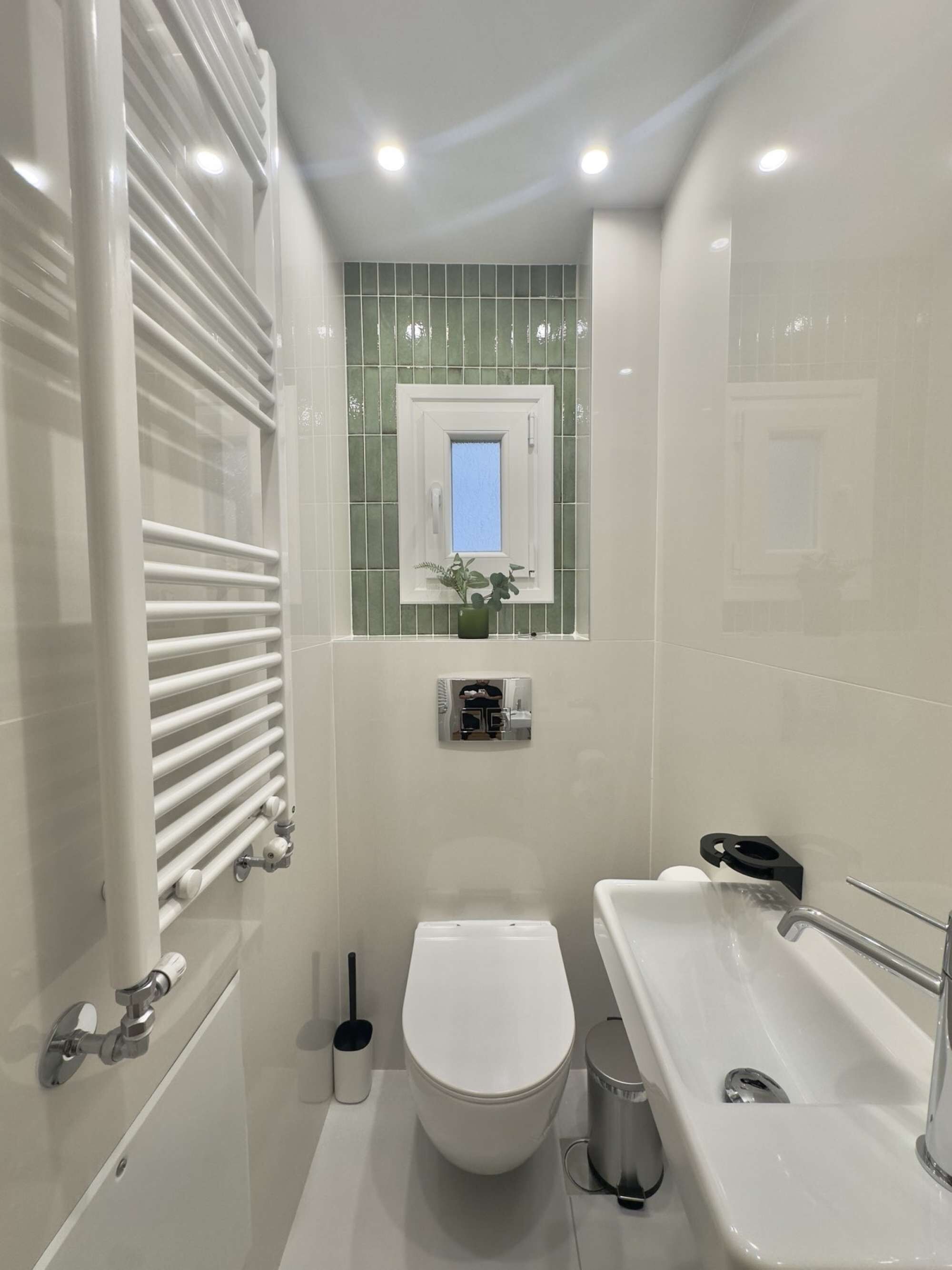 A modern bathroom with a white toilet, a bathtub, and a shower area with a white radiator.