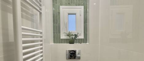 A modern bathroom with a white toilet, a bathtub, and a shower area with a white radiator.