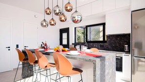 Une cuisine moderne dotée d’un îlot central, d’appareils électroménagers en acier inoxydable et d’un coin repas avec des tabourets de bar.