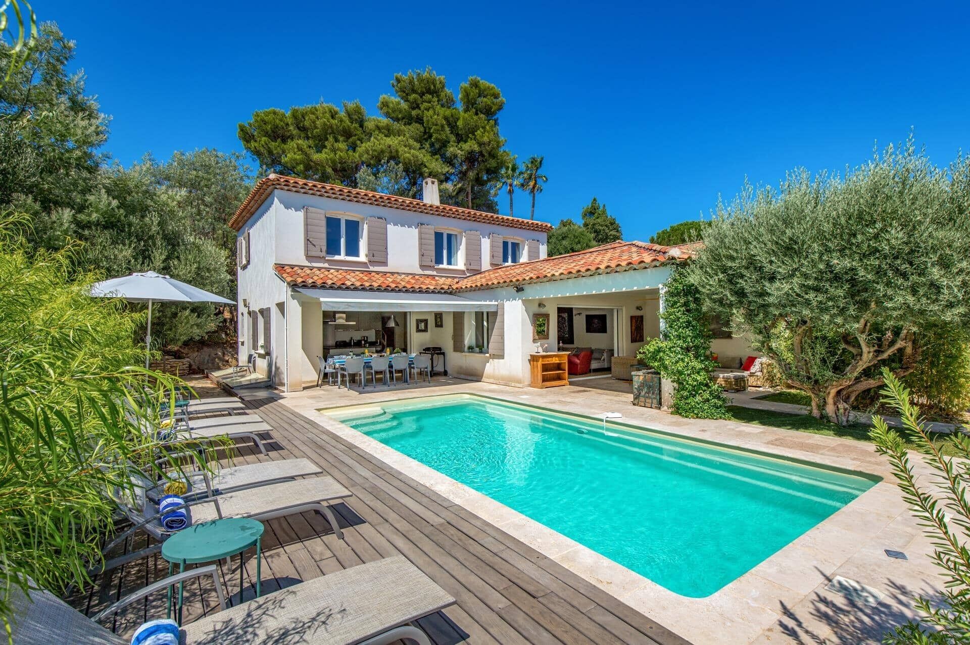 A two-story house with a swimming pool, outdoor seating, and a covered patio area.