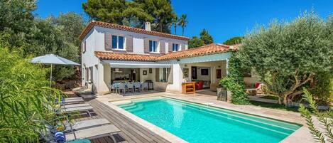 A two-story house with a swimming pool, outdoor seating, and a covered patio area.